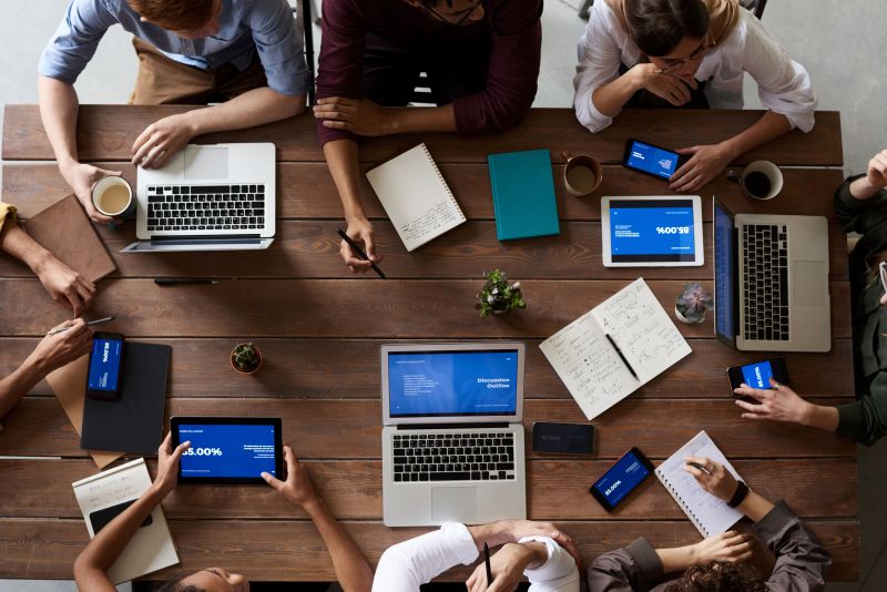 Une petite équipe travaille autour d’une table avec ses ordinateurs et documents.